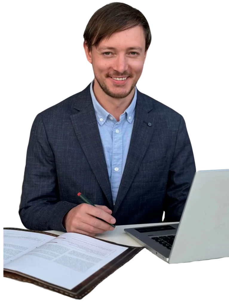 Markus Garth, ein Business-Experte im Sakko, sitzt mit einem Laptop und Dokumenten an einem Tisch. Er lächelt freundlich und zeigt eine professionelle, aufgeschlossene Haltung.